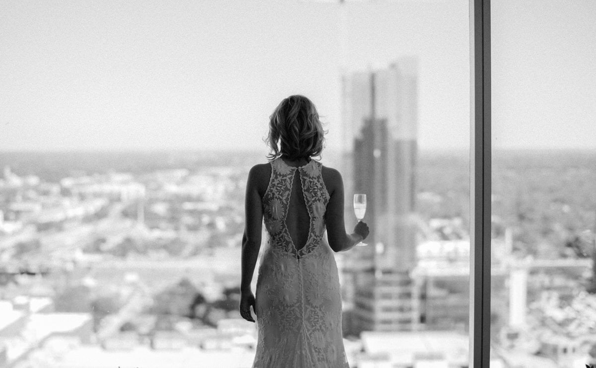 bride enjoying the city view with a glass of champagne