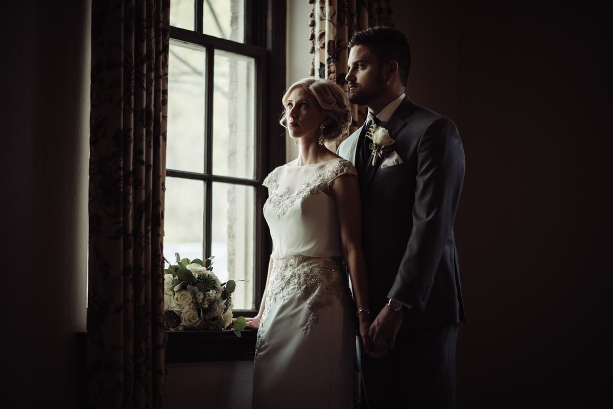 window portrait of bride and groom