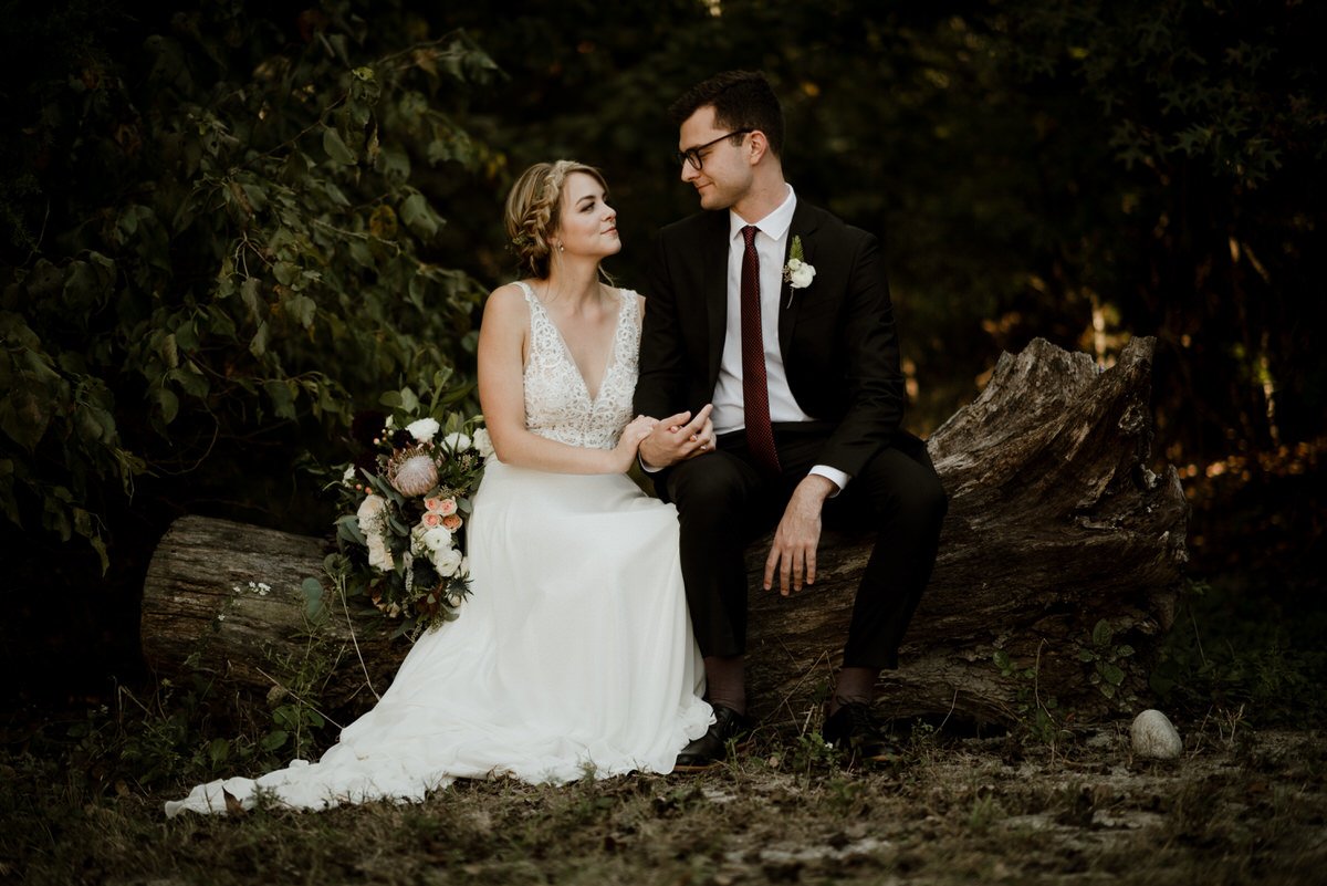 bride and groom sitting on tree log