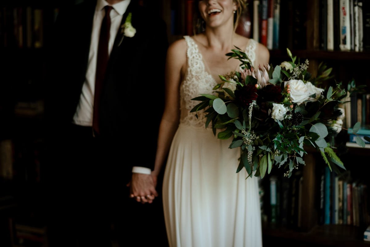 bride laughing while holding grooms hand