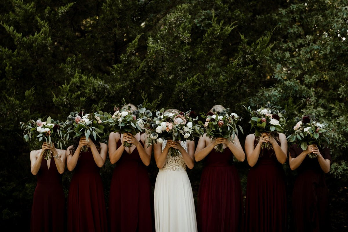 bride and bridesmaids holding bouquets over face