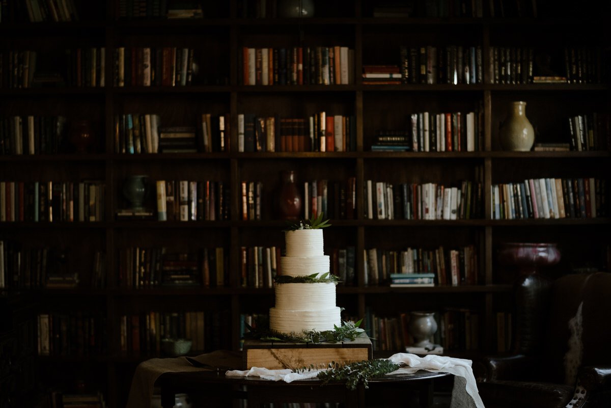 wedding cake displayed in front of bookshelves