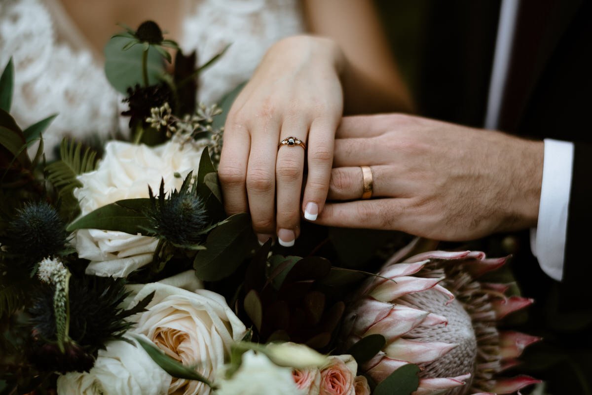 detail shot of rings on hand with bouquet