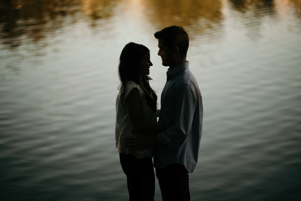 silhouette of couple by lake