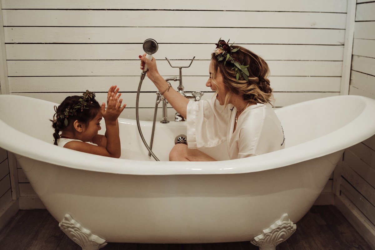 bride and flower girl being playful in bathtub