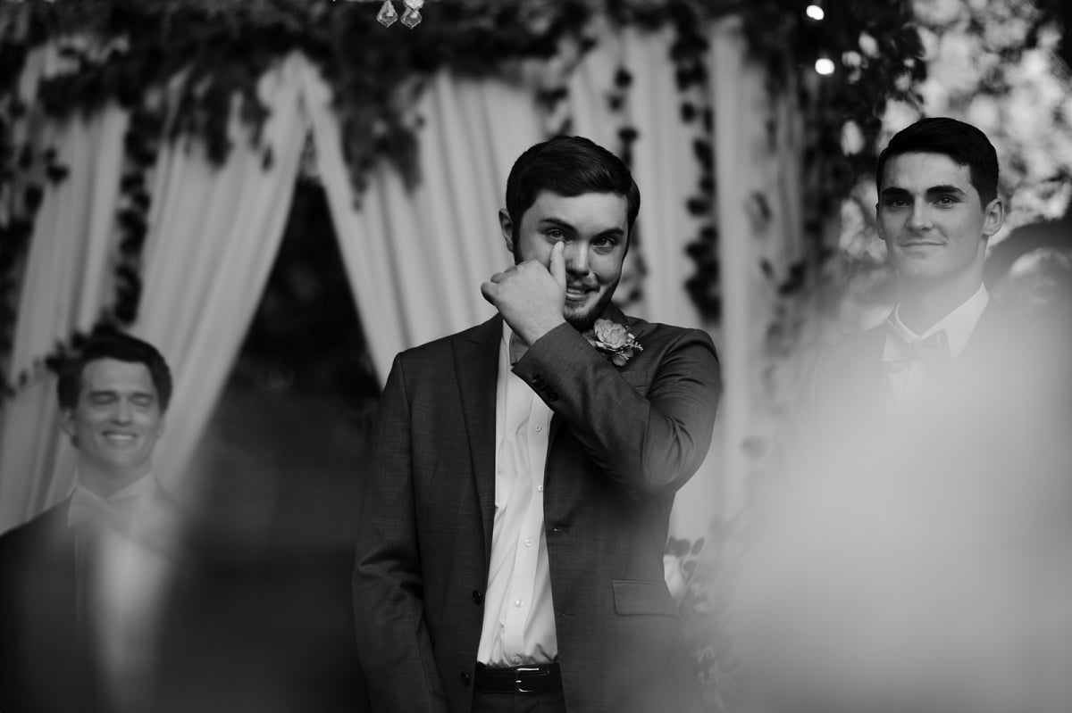 groom wipes away tears after first look