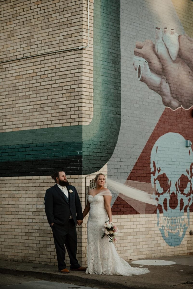 wedding couple pose in front of mural