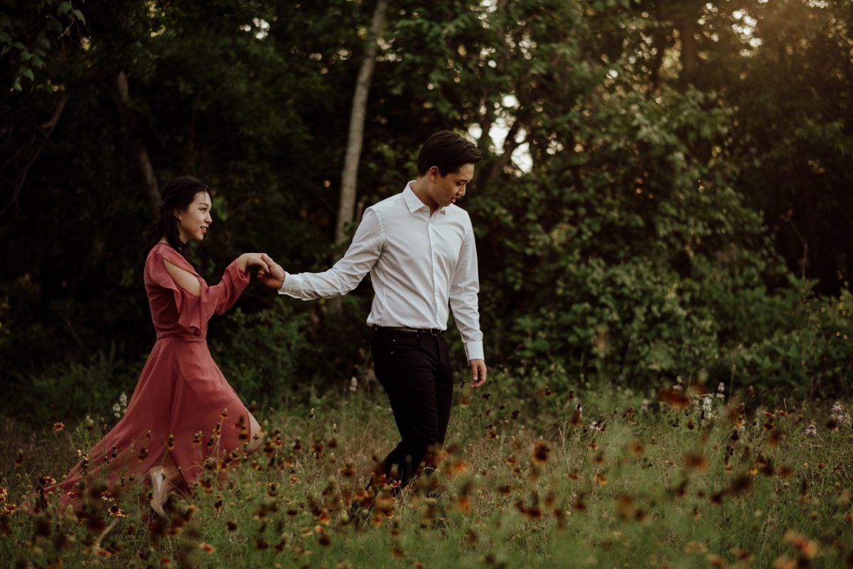 couple walks through wild flowers