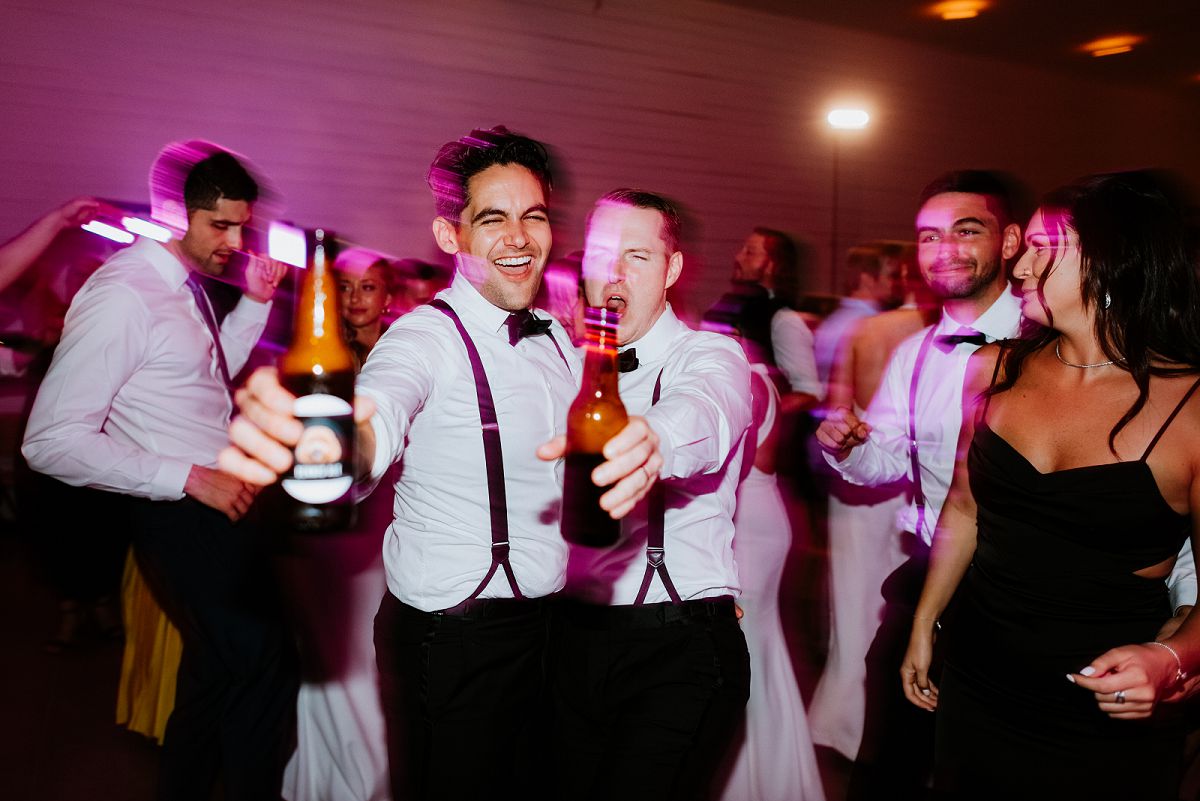 gay couple on dance floor toasting with beer
