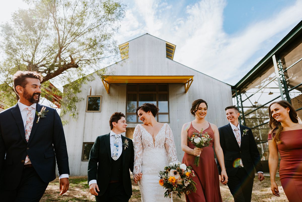 wedding party walking in front of venue smiling