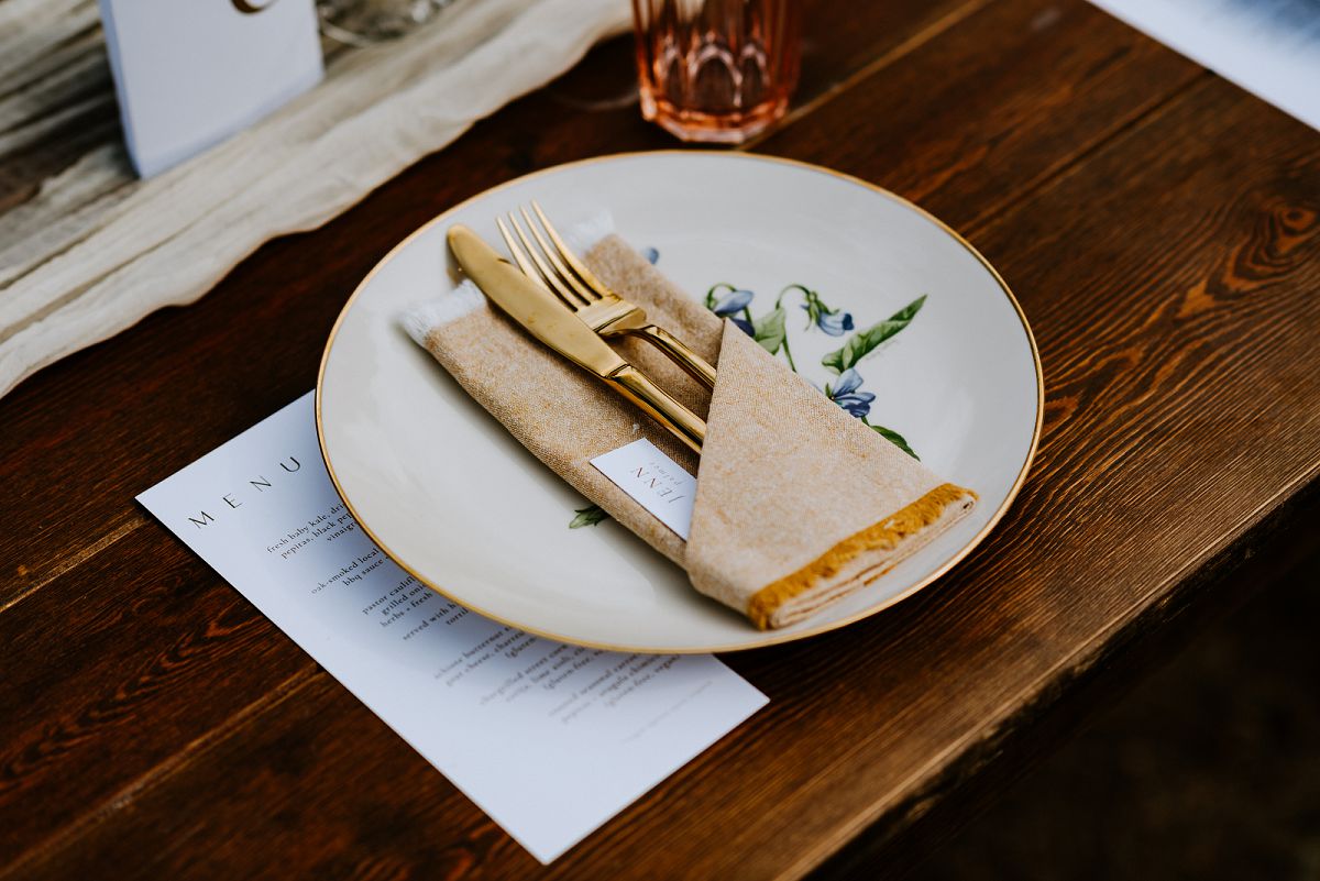 close up of neutral toned plate setup with gold silverware