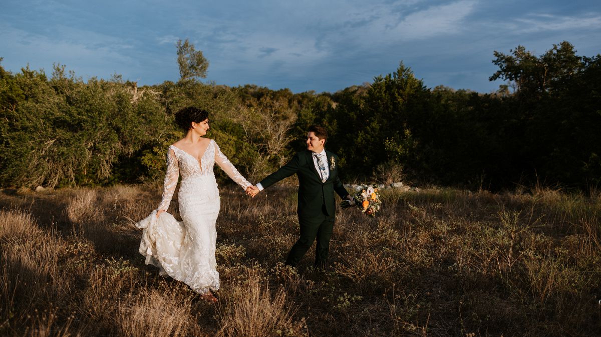 brides walking through field during sunset