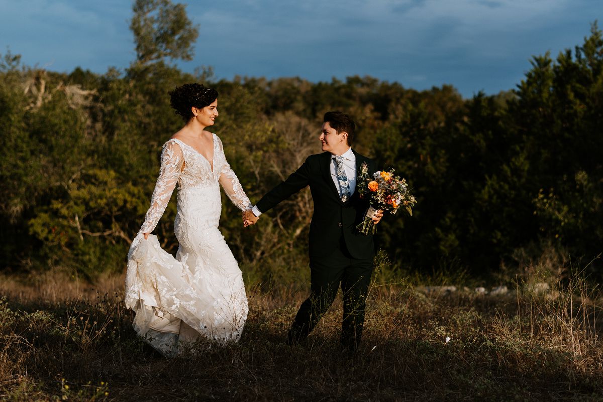 brides walking through field during sunset