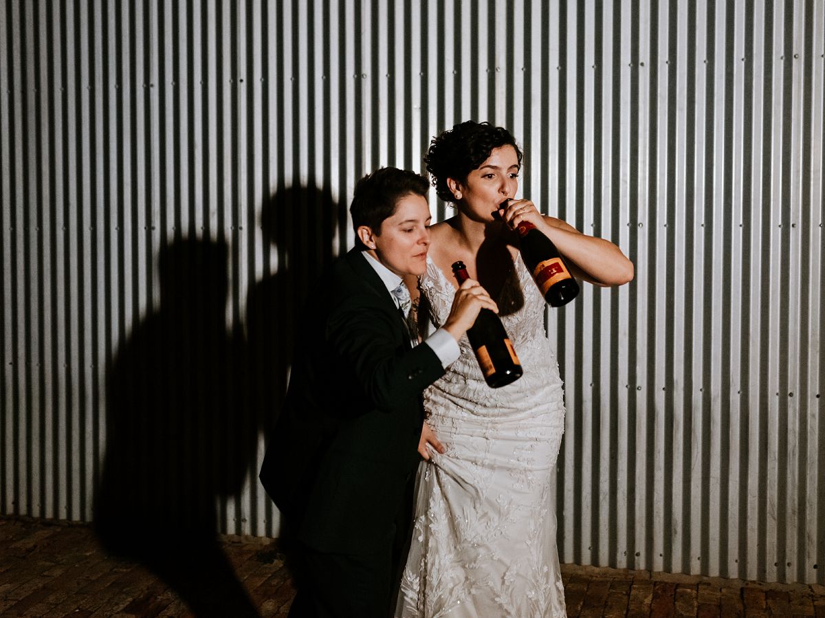 brides spraying champagne bottle at night 