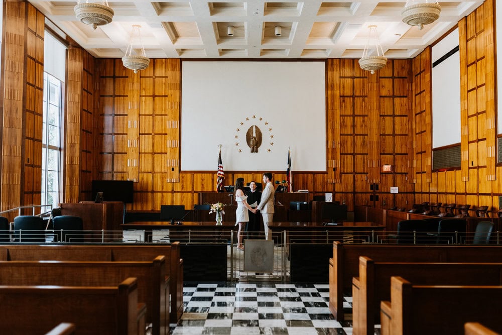 couple eloping with judge in large courthouse room