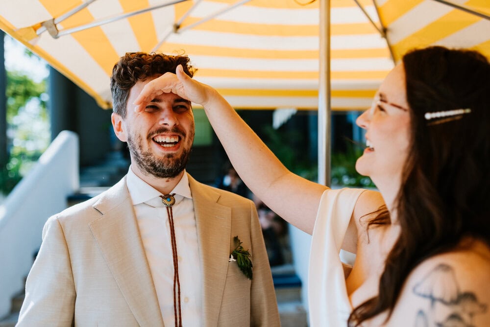 bride wiping sweat from grooms forehead while smiling