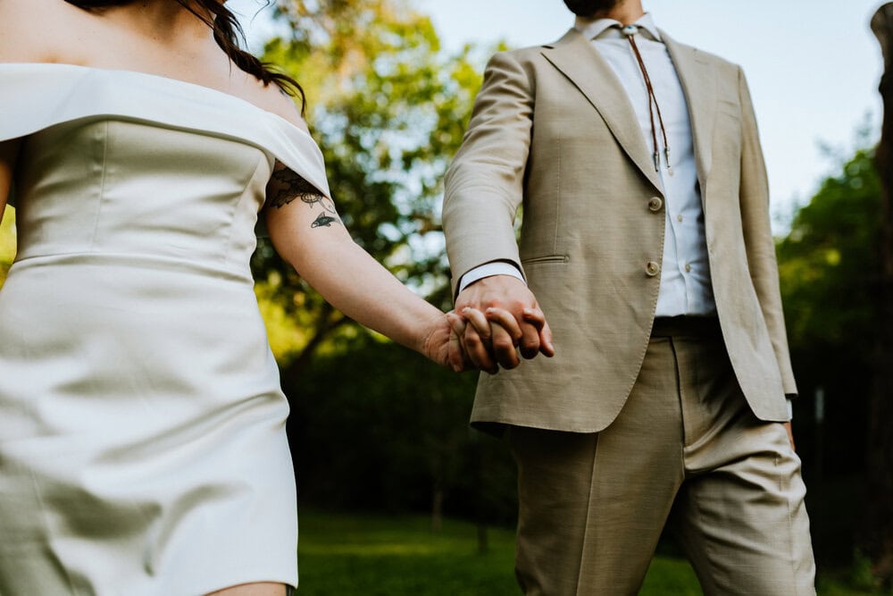 close up of hands while couple walks through grass