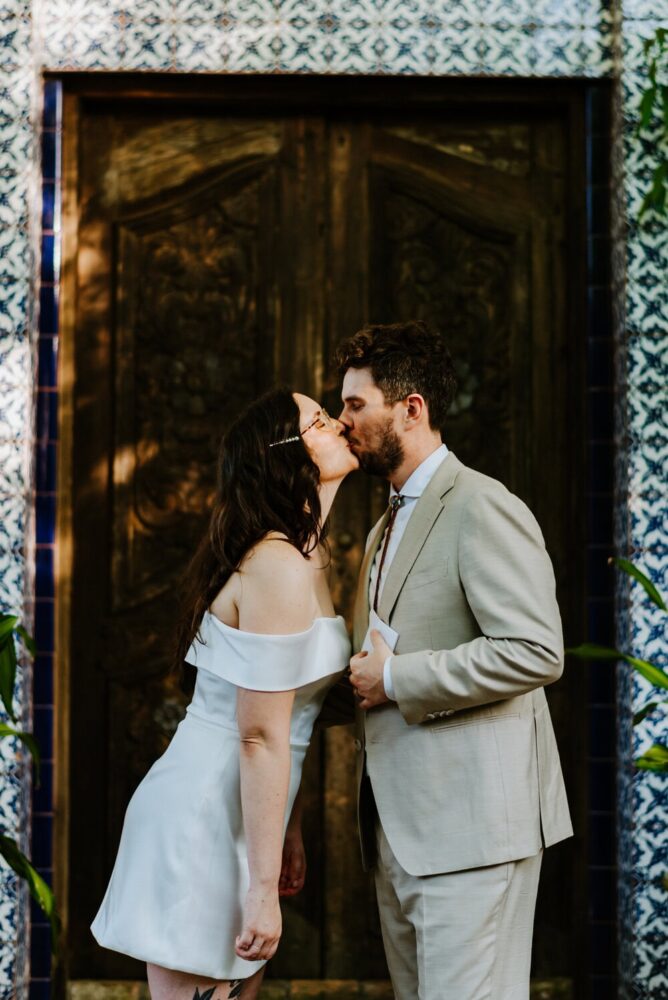 couple kissing in front of large wooden doors after giving private vows