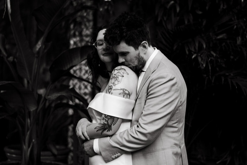 groom holding bride with tattoos showing in black and white image