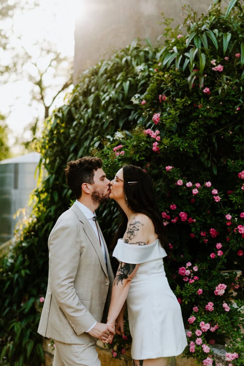 couple kissing in front of pink flowers