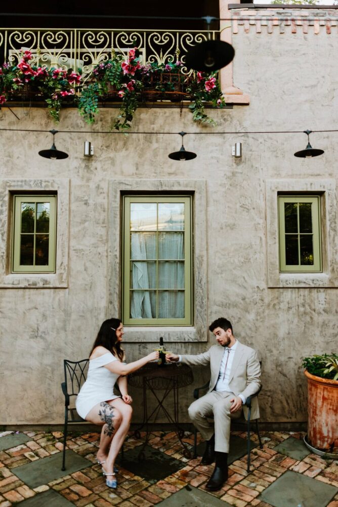 couple toasts to each other across small table in wide photo
