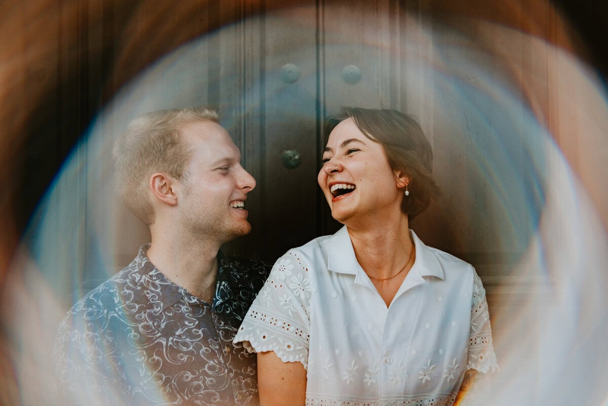 couple facing each other laughing with lens effect circling around them