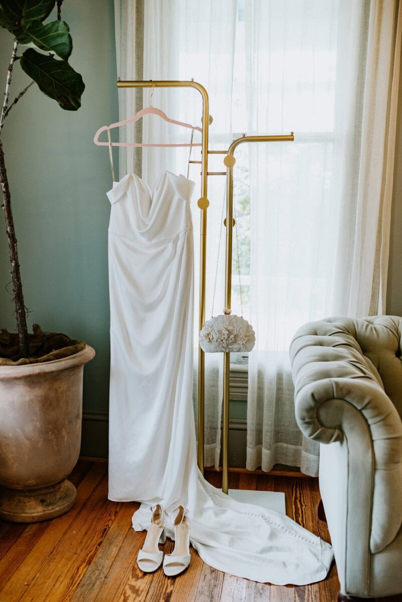 modern wedding dress hanging on gold stand indoors