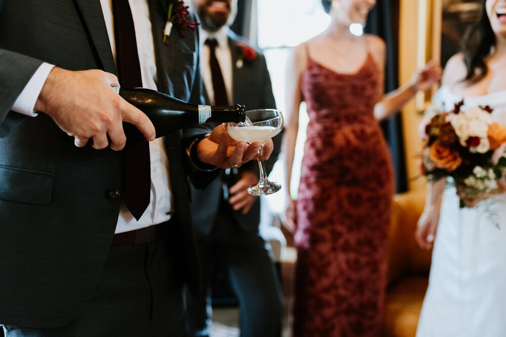 couple with wedding party share a toast indoors