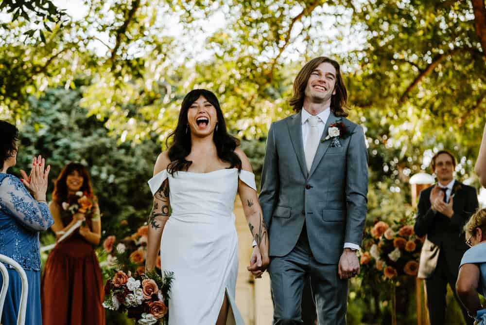 bride and groom laughing and smiling while walking down aisle
