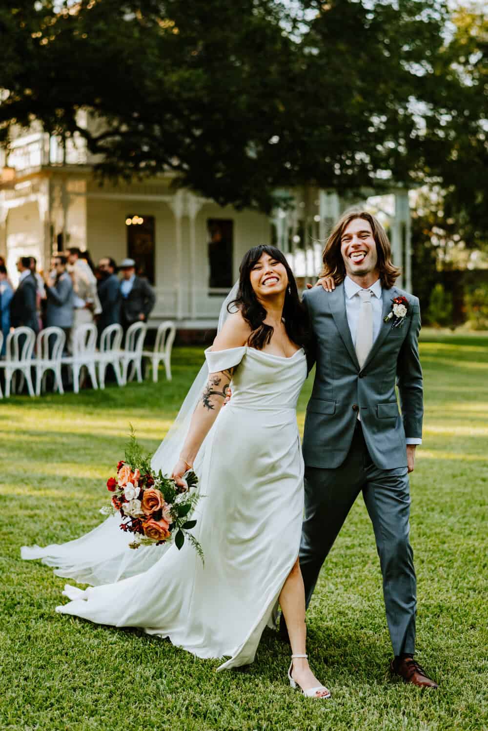 couple looks at camera after walking down aisle while bride smiles and groom sticks out tongue