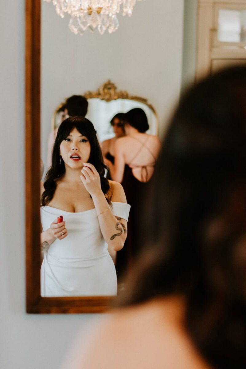 bride applying lipstick in mirror