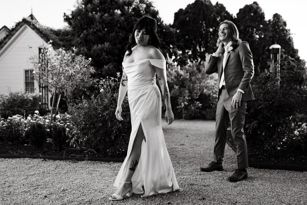 editorial style black and white photo of bride in front of groom showing off dress