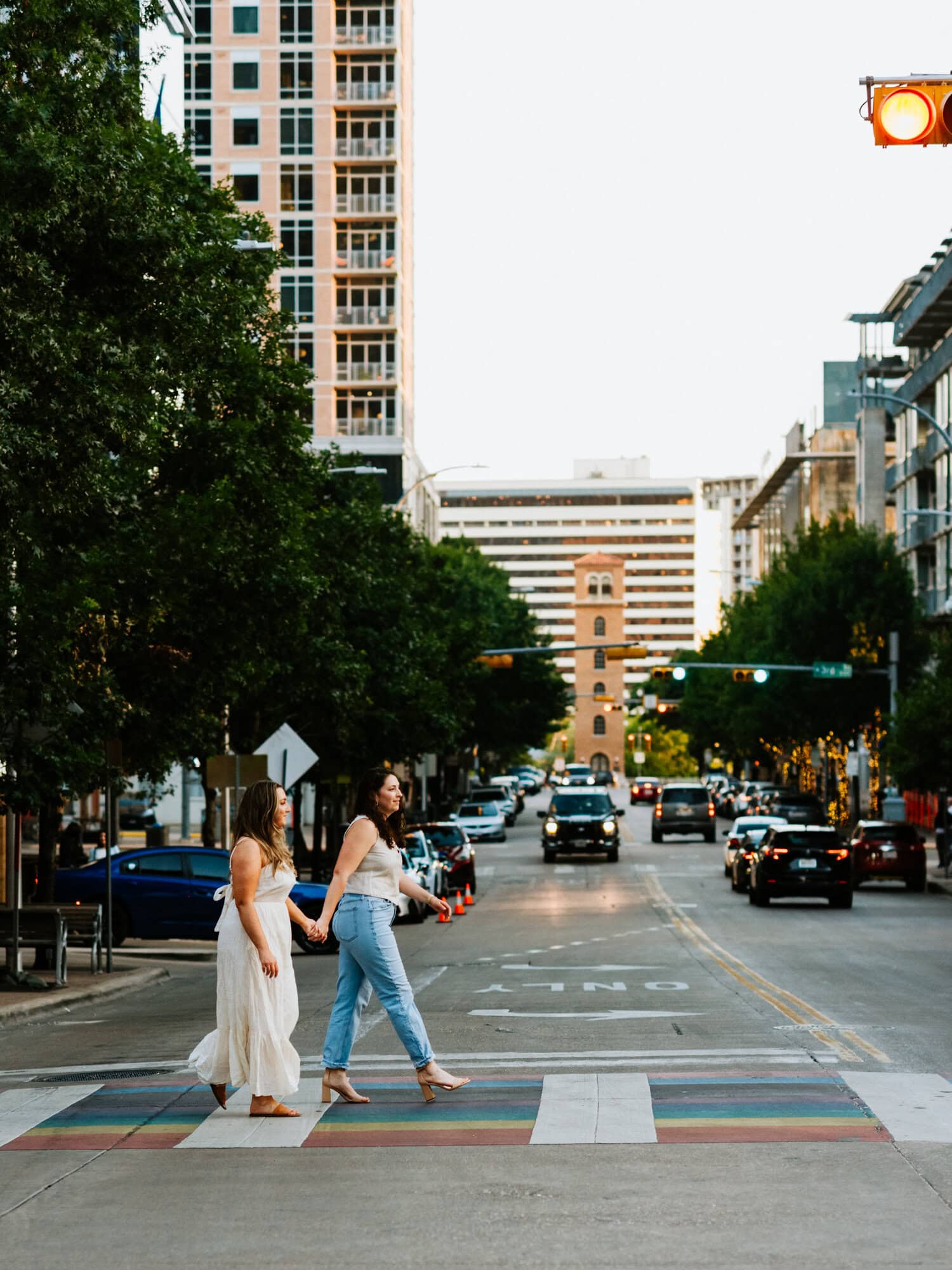 lesbian couple walking across rainbow crosswalk in downtown