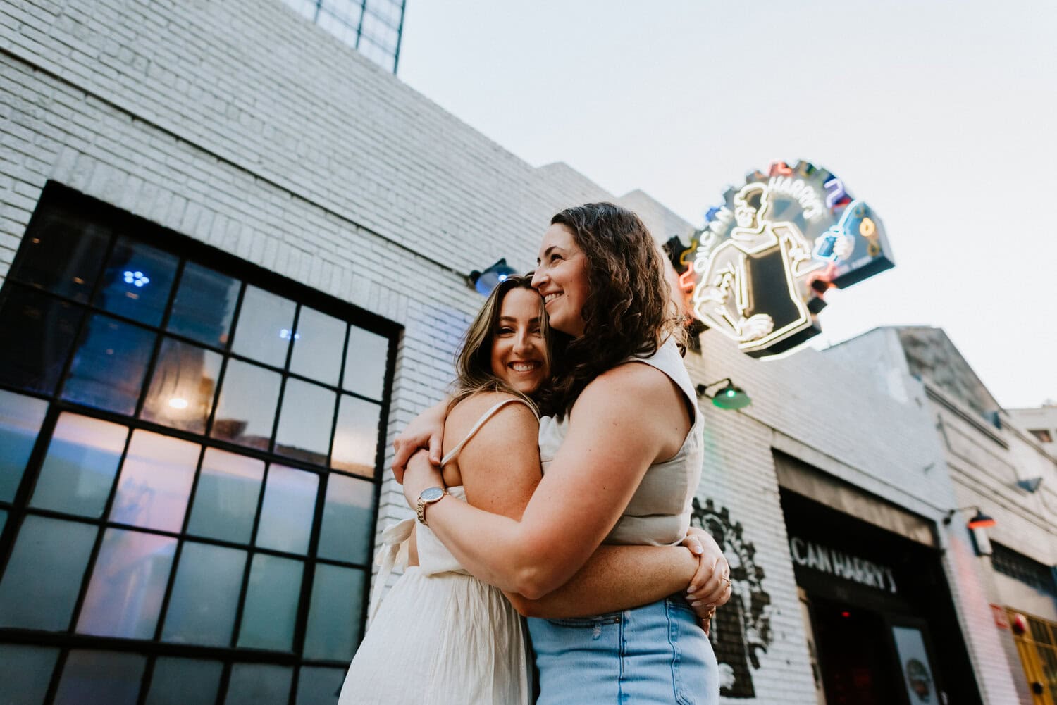 lesbian couple holding each other close on sidewalk