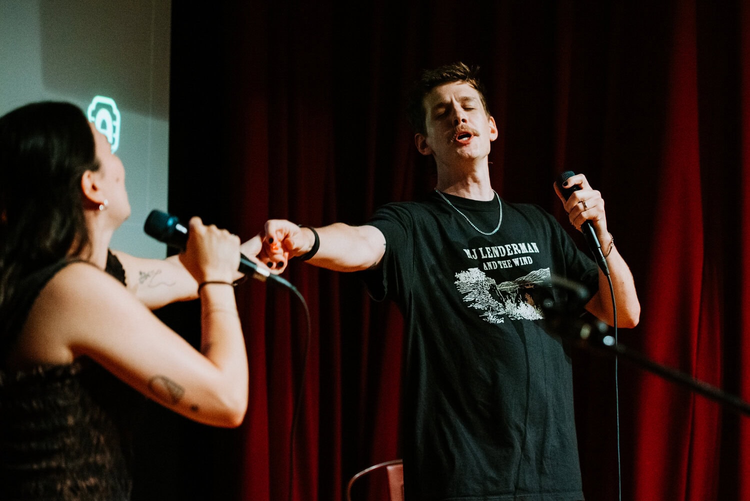 friends singing karaoke on stage at barrel o' fun during wedding reception