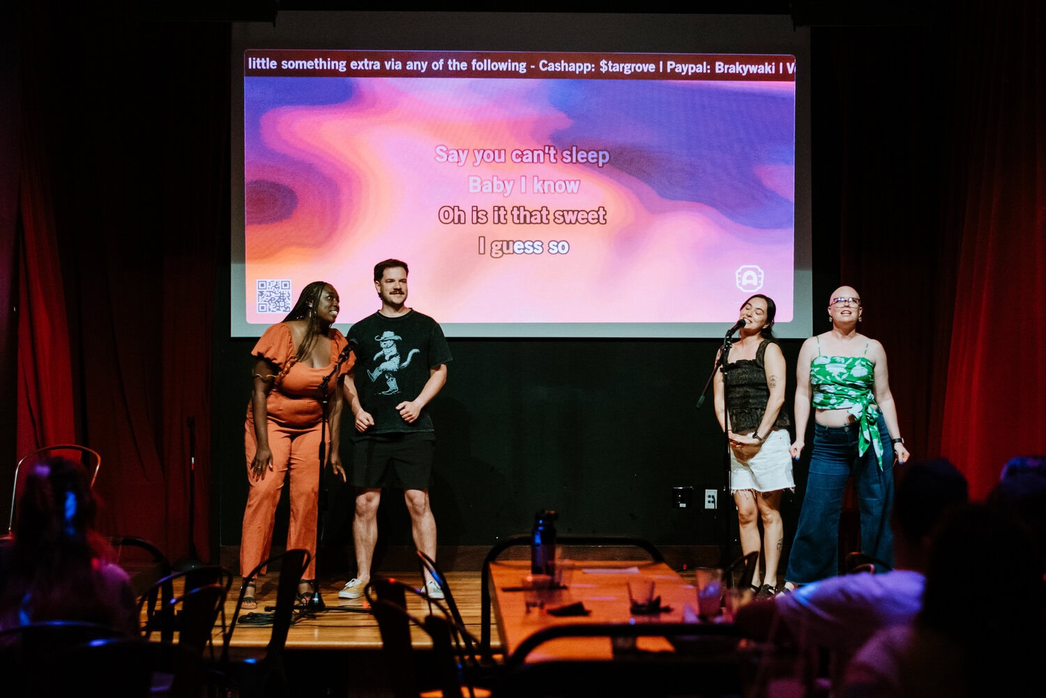 friends singing karaoke on stage at barrel o' fun during wedding reception